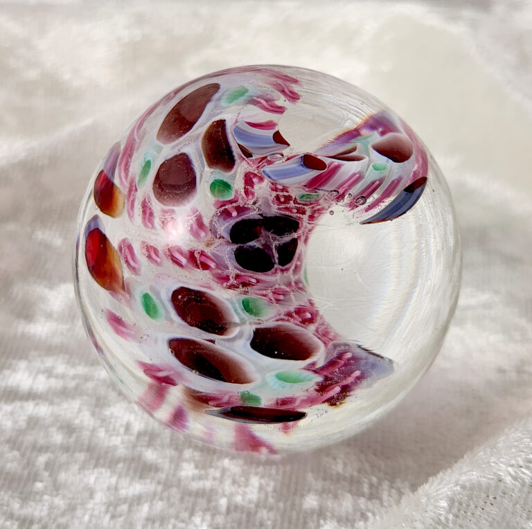 Clear marble with a curling band of red, pink and green glass
