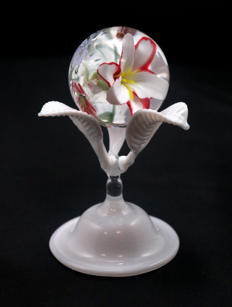 Marble with a white and red lily inside, on a white glass flower-shaped stand