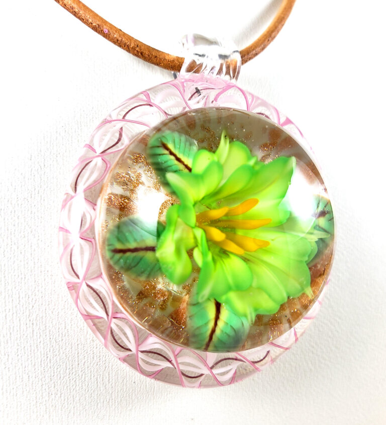 Pendant with a bright green flower inside a pink and white lattice rim