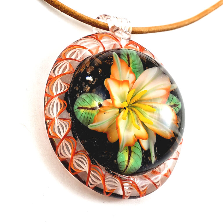 Pendant with an orange and cream lily on black, in an orange lattice rim, on a leather cord