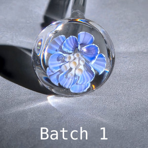 Test bloom of Light Blue Dahlia 3-D murrine cane batch 1: ruffled light blue petals with delicate white stripes around a cluster of cream stamens, in a clear borosilicate sphere