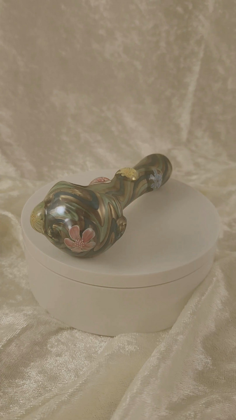 Glass spoon pipe with murrine flowers on a white stand (video)