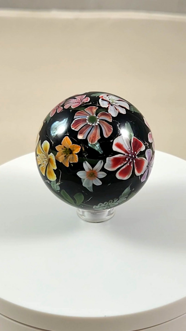 Black marble covered with multicolored murrine flowers on a white stand (video)